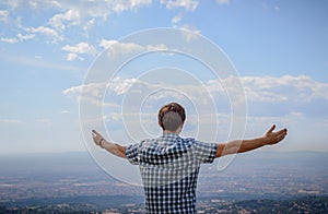 A young man overlooking the landscape from the hill with his arm