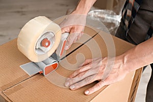 Young man packing moving box indoors