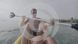 Young man paddling the sea kayak in the tropical calm ocean.
