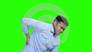 Young man with pain in kidneys on green screen.