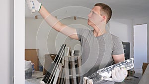 Young man painting wall with paint roller in apartment during repair works. Teenager working on part-time job in