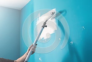 Young man painting wall with paint roller. Man at work concept