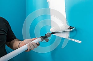 Young man painting wall with paint roller. Man at work concept