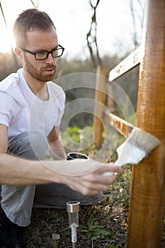Young man painting wooden fence in his backyard
