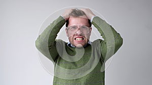 The young man with a panic attack is desperately tearing his hair on his head