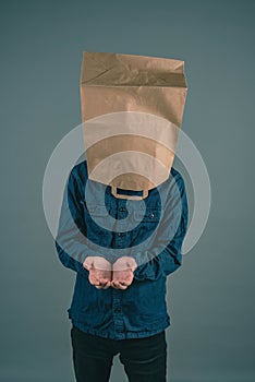 Young man with paper bag on his head, open hands for begging