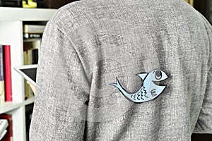 Young man with a paper fish attached to his back photo