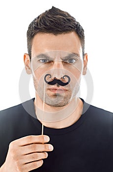 Young man with paper moustaches making faces isolated on white b