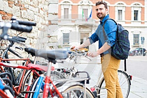 Young man parking bicycle outdoors in the city