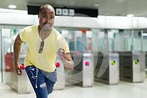 Young man passenger running to train at modern metro station