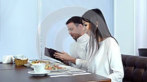 Young man paying the bill while his girlfriend checking her phone