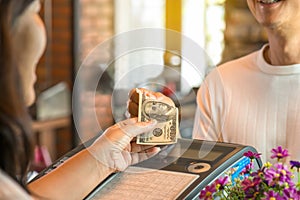 Young man paying cash at register counter .