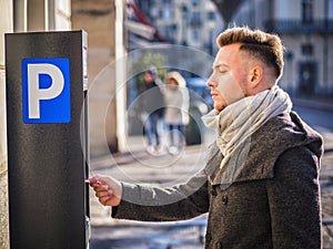 Young man paying for a parking ticket at machine