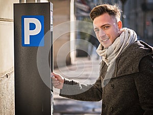 Young man paying for a parking ticket at machine