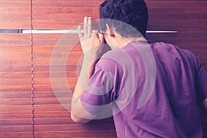 Young man peeping out through venetian blinds