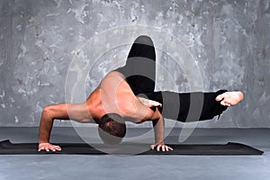 Young man performing a Eka Pada Danda Kaundiniasana