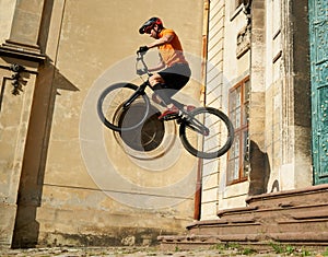 Young man performing a radical mountain bike jumps in old town