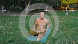 Young Man Performs Asanas of Yoga, Doing Gymnastics on a Glade in the Forest