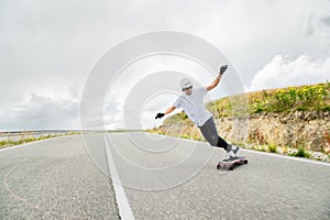 A young man performs a complicated stunt on a longboard
