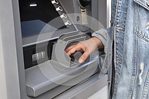 The young man performs his transactions from the bank ATM