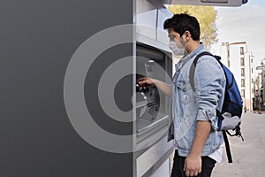 The young man performs his transactions from the bank atm using his protective mask