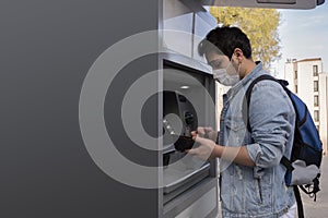 The young man performs his transactions from the bank atm using his protective mask photo