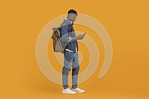 Young man with phone and backpack facing away
