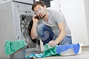 young man on phone durin washing machine repair service