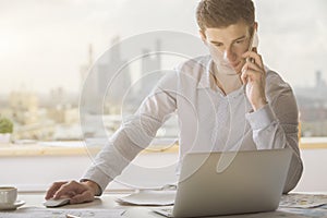 Young man on phone using laptop