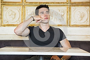 Young man phoning while sitting in cafe