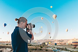 Young man photographer making pictures of air balloons at sunrise time in Cappadocia