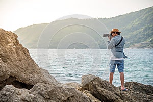 Young man photographer taking photos on the rock