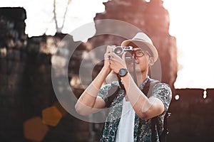 Young Man Photographer Traveler with backpack taking photo with his retro film camera, Great wall in background at historical