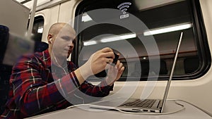 A young man photographs a telephone computer screen while on the train.