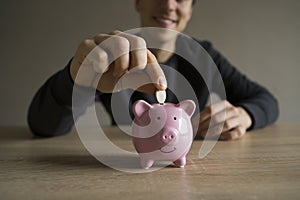 Young man with a piggy pank, takes care about his savings