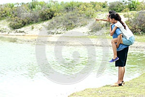 Young man piggybacking his girlfriend at lakeside