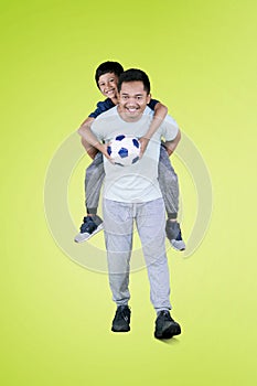 Young man piggybacks his son after playing football