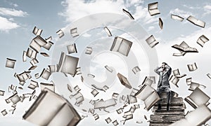 Young man on pile of books dont want to hear anything