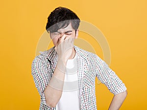 Young man pinches nose with fingers .  disgust something stinks bad smell photo