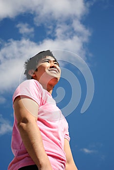 Young man in a pink shirt against the blue sky