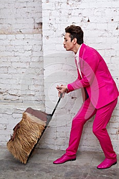 Young man in pink suit pulls roller bag