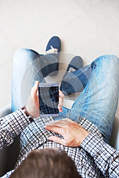 A young man in a plaid shirt with a smartphone in his hand. Touch screen phone business.