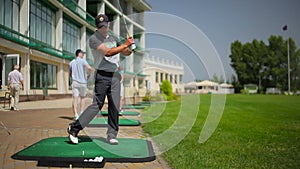 The young man play golf near th clubhouse