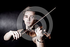 Young man play violin on dark background