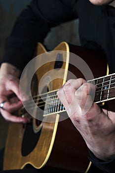 Young man playing on acoustic guitar.