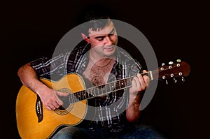 Young man playing acoustic guitar - on black