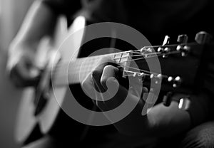 Young man playing acoustic guitar in black and white. Close-up