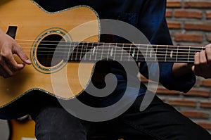 A young man playing acoustic guitar happily in the music room.