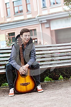 Young man playing on acoustic guitar outdoor