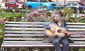 Young man playing on acoustic guitar outdoor